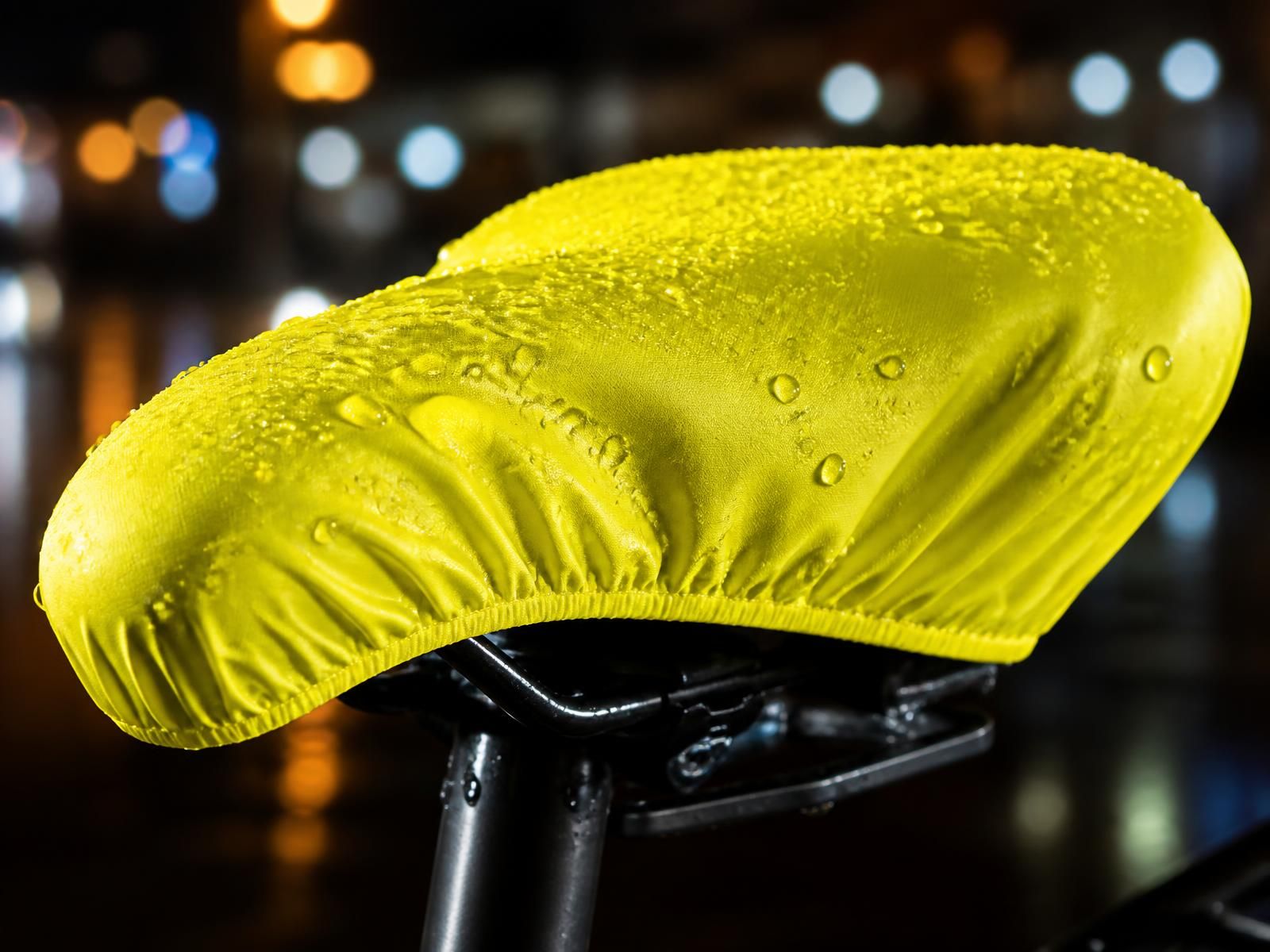 Close-up of a waterproof neon yellow bicycle seat cover beaded with rainwater
